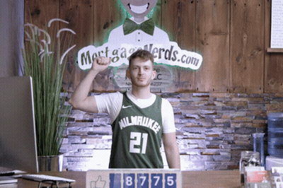 A Man Wearing A Milwaukee Jersey Stands In Front Of A Sign That Says Mortga Nerds.com GIF