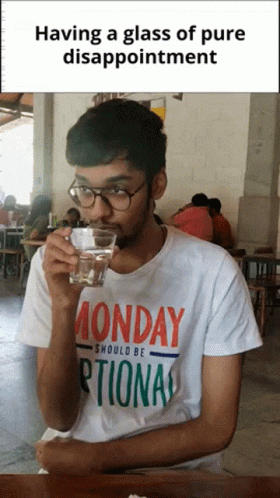 A Man Wearing A Monday Shirt Drinks From A Glass Of Water GIF