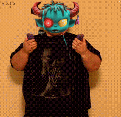 A Man Wearing A Monster Mask Is Holding A Pair Of Remote Controls GIF