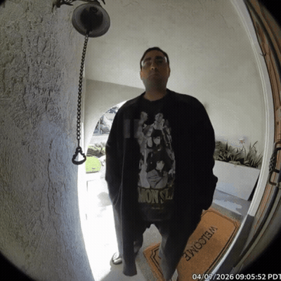 A Man Wearing A Monsters Shirt Stands In Front Of A Door GIF