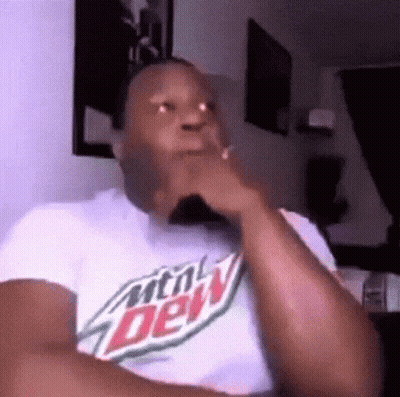 A Man Wearing A Mountain Dew T-Shirt Is Sitting In A Chair With His Hand On His Chin . GIF