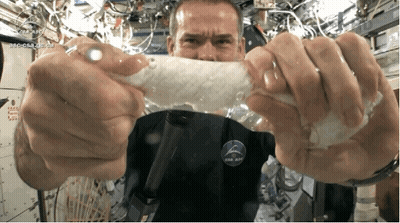A Man Wearing A Nasa Shirt Is Holding A Piece Of Plastic GIF