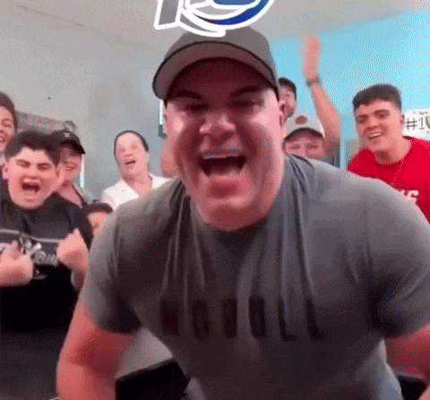 A Man Wearing A Naval Shirt Is Laughing In Front Of A Crowd Of People GIF