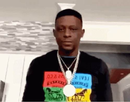 A Man Wearing A Necklace And A Medal Around His Neck Is Standing In A Room . GIF