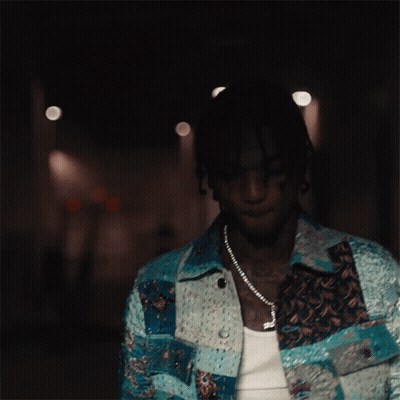A Man Wearing A Necklace With A Cross On It Looks Down GIF