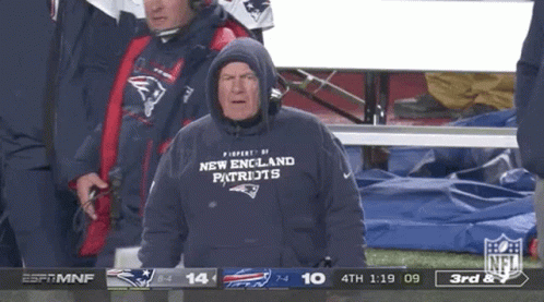 A Man Wearing A New England Patriots Sweatshirt Is Watching A Football Game GIF