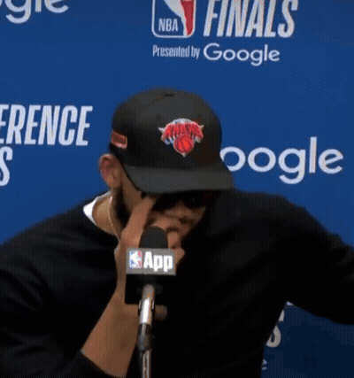 A Man Wearing A New York Knicks Hat Talks Into A Microphone At A Nba Finals Press Conference GIF