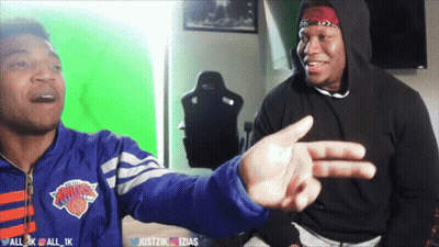 A Man Wearing A New York Knicks Jacket Is Pointing At Another Man GIF