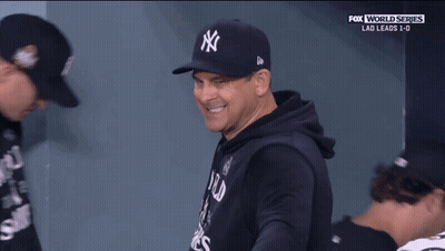 A Man Wearing A New York Yankees Hat Is Smiling During A Fox World Series Game GIF