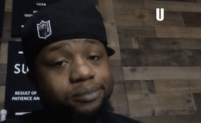 A Man Wearing A Nfl Hat Says " U Already " In Front Of A Wooden Wall GIF