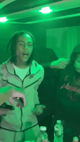 A Man Wearing A Nike Jacket Is Dancing In A Dark Room GIF