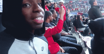 A Man Wearing A Nike Jacket Is Sitting In The Stands GIF