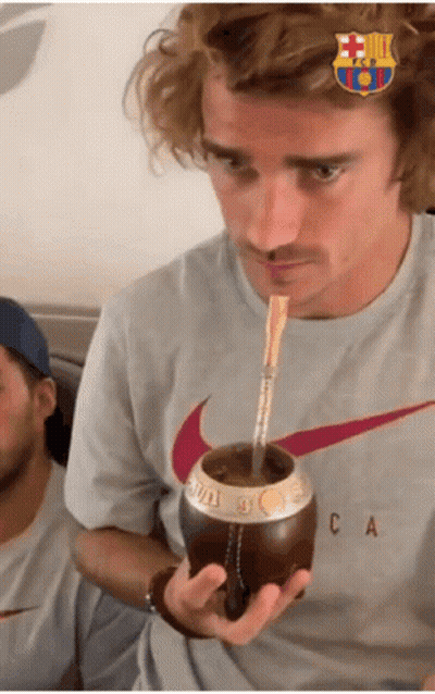 A Man Wearing A Nike Shirt Drinks From A Cup With A Straw GIF
