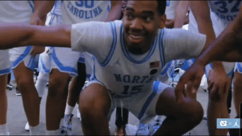 A Man Wearing A North Carolina Jersey Is Squatting Down GIF