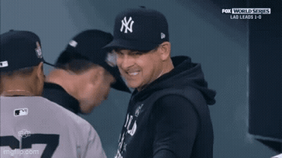 A Man Wearing A Ny Hat Is Smiling While Standing Next To Two Other Men GIF