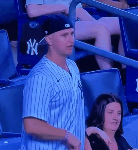 A Man Wearing A Ny Yankees Jersey Stands In A Stadium GIF