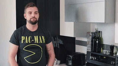 A Man Wearing A Pac-Man T-Shirt Stands In A Kitchen GIF