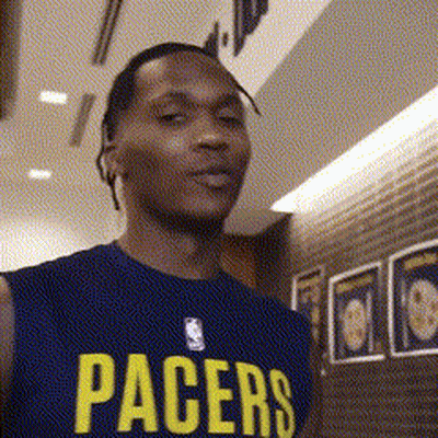 A Man Wearing A Pacers Jersey Stands In Front Of A Brick Wall GIF