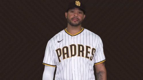 A Man Wearing A Padres Jersey Is Standing In Front Of A Brown Background GIF
