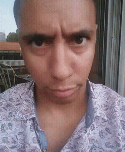 A Man Wearing A Paisley Shirt Looks At The Camera With A Serious Look On His Face GIF