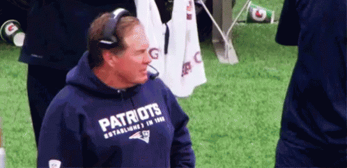 A Man Wearing A Patriots Hoodie Is Standing On A Field . GIF