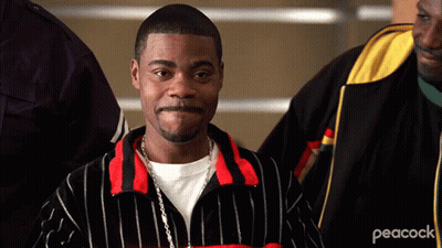 A Man Wearing A Peacock Jacket Is Standing In A Crowd Of People GIF