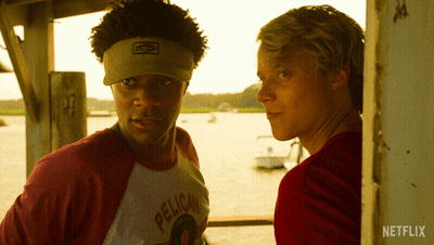 A Man Wearing A Pelican Shirt Stands Next To Another Man In A Red Shirt GIF