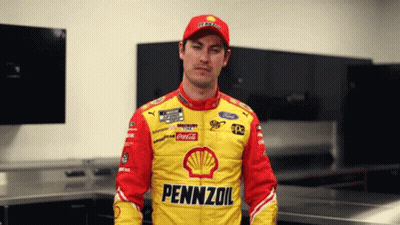 A Man Wearing A Pennzoil Jacket Stands In A Room GIF
