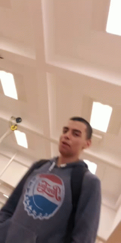 A Man Wearing A Pepsi Sweatshirt Stands In A Room GIF