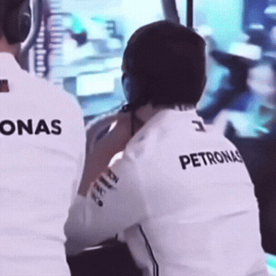 A Man Wearing A Petronas Shirt Is Sitting In Front Of A Monitor GIF