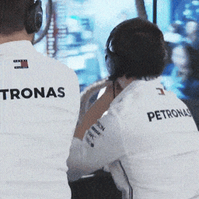 A Man Wearing A Petronas Shirt Sits In Front Of A Monitor GIF
