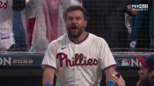 A Man Wearing A Phillies Jersey Is Standing In The Dugout GIF