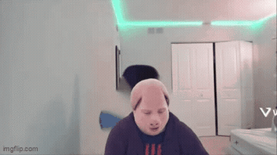 A Man Wearing A Pig Mask Is Standing In A Room With A Green Light On The Ceiling . GIF