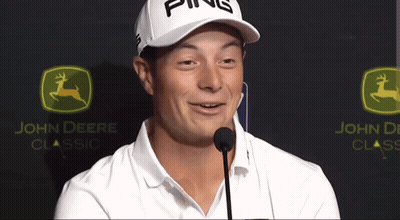 A Man Wearing A Ping Hat Stands In Front Of A John Deere Logo GIF