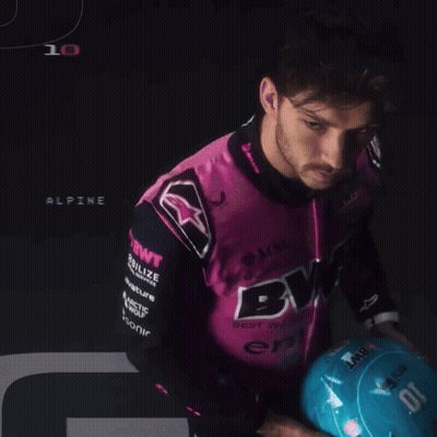 A Man Wearing A Pink And Black Shirt That Says Bwt Holds A Blue Helmet GIF