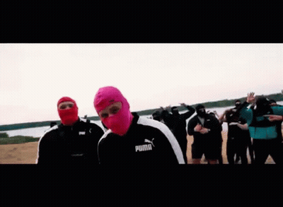 A Man Wearing A Pink Balaclava Is Standing In Front Of A Group Of People . GIF