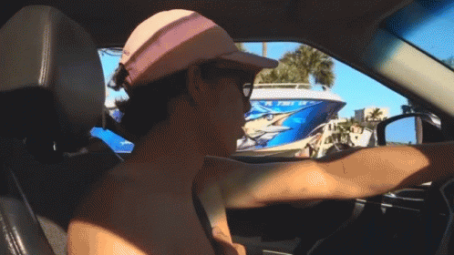 A Man Wearing A Pink Hat Is Driving A Car With A Boat In The Background That Says Florida On It GIF