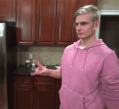 A Man Wearing A Pink Hoodie Is Pointing At Something GIF