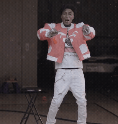 a man wearing a pink jacket and white pants is standing in front of a table with the word patterns on it