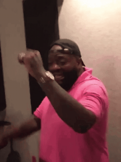 A Man Wearing A Pink Shirt And A Hat Is Dancing . GIF