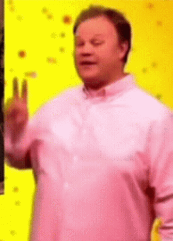 A Man Wearing A Pink Shirt Is Giving A Peace Sign . GIF