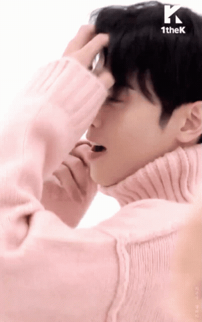 A Man Wearing A Pink Sweater Is Covering His Face With His Hand GIF