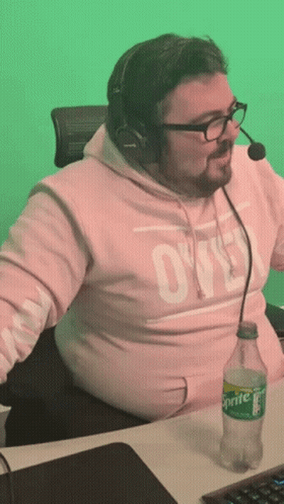 A Man Wearing A Pink Sweatshirt With The Word Ovo On It Sits At A Desk With A Sprite Bottle In Front Of Him GIF