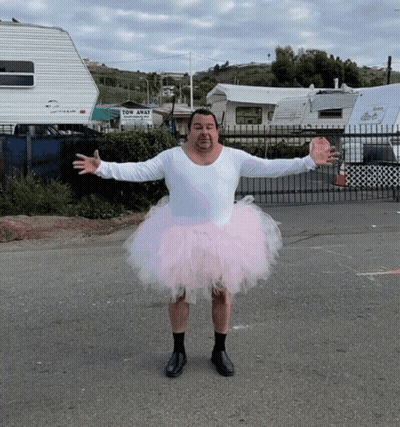 A Man Wearing A Pink Tutu Stands In Front Of A Tow Away Sign GIF