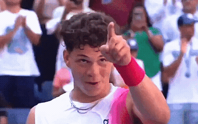 A Man Wearing A Pink Wristband Is Giving A Thumbs Up In Front Of A Crowd . GIF