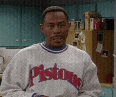 A Man Wearing A Pistons Sweatshirt Is Standing In Front Of A Refrigerator GIF