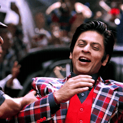 A Man Wearing A Plaid Jacket And A Red Vest Laughs GIF