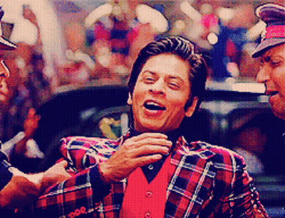 A Man Wearing A Plaid Jacket And A Red Vest Laughs GIF