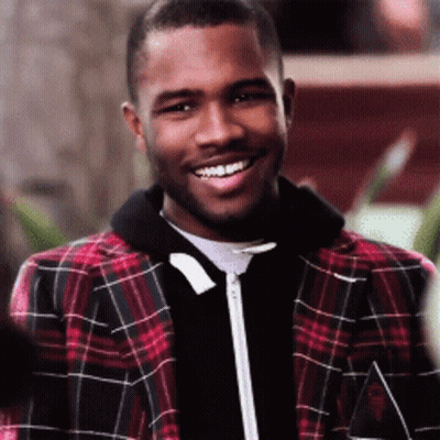 A Man Wearing A Plaid Jacket Is Smiling And Looking At The Camera GIF
