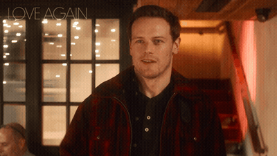 A Man Wearing A Plaid Jacket Is Standing In Front Of A Sign That Says Love Again GIF